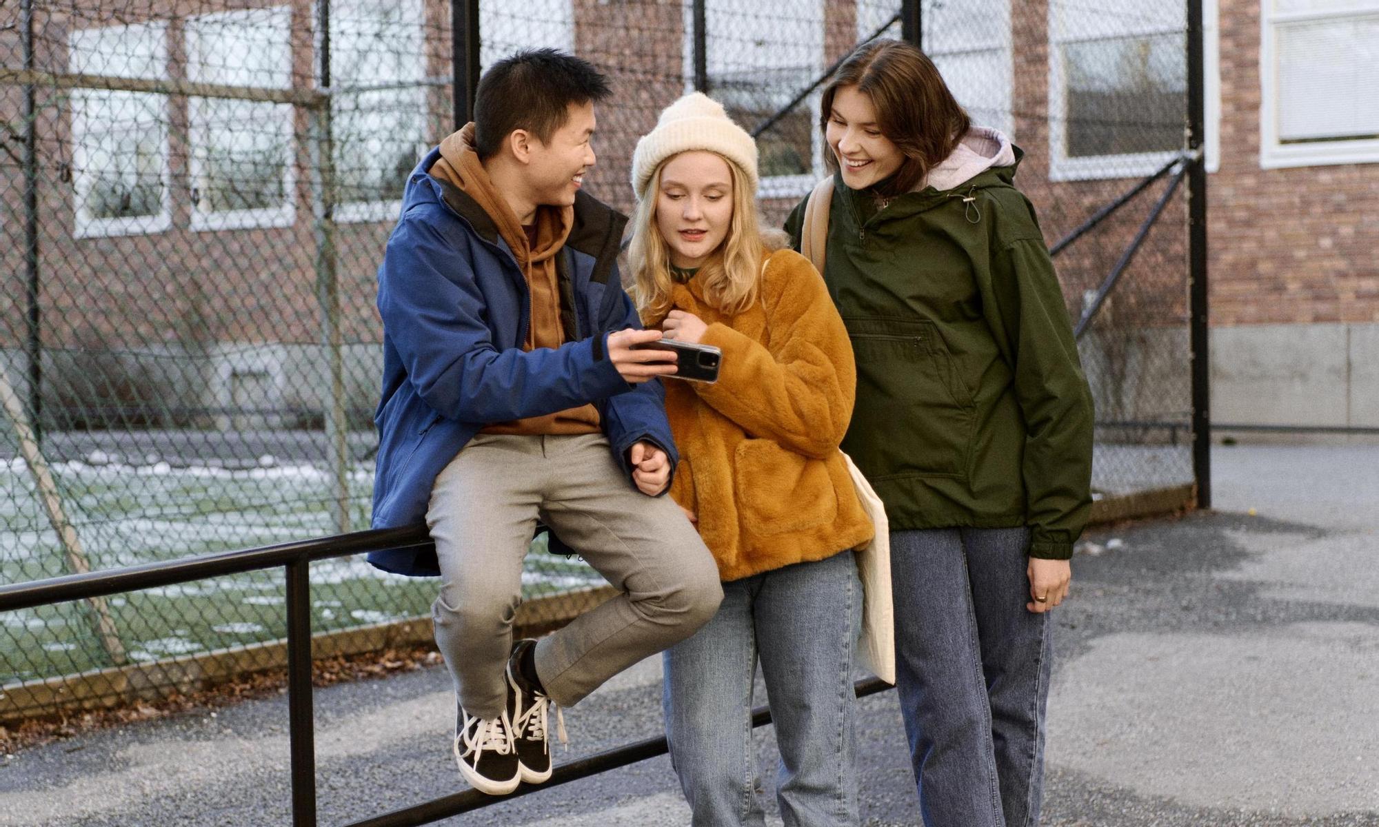 Students hanging outside school looking at a mobile