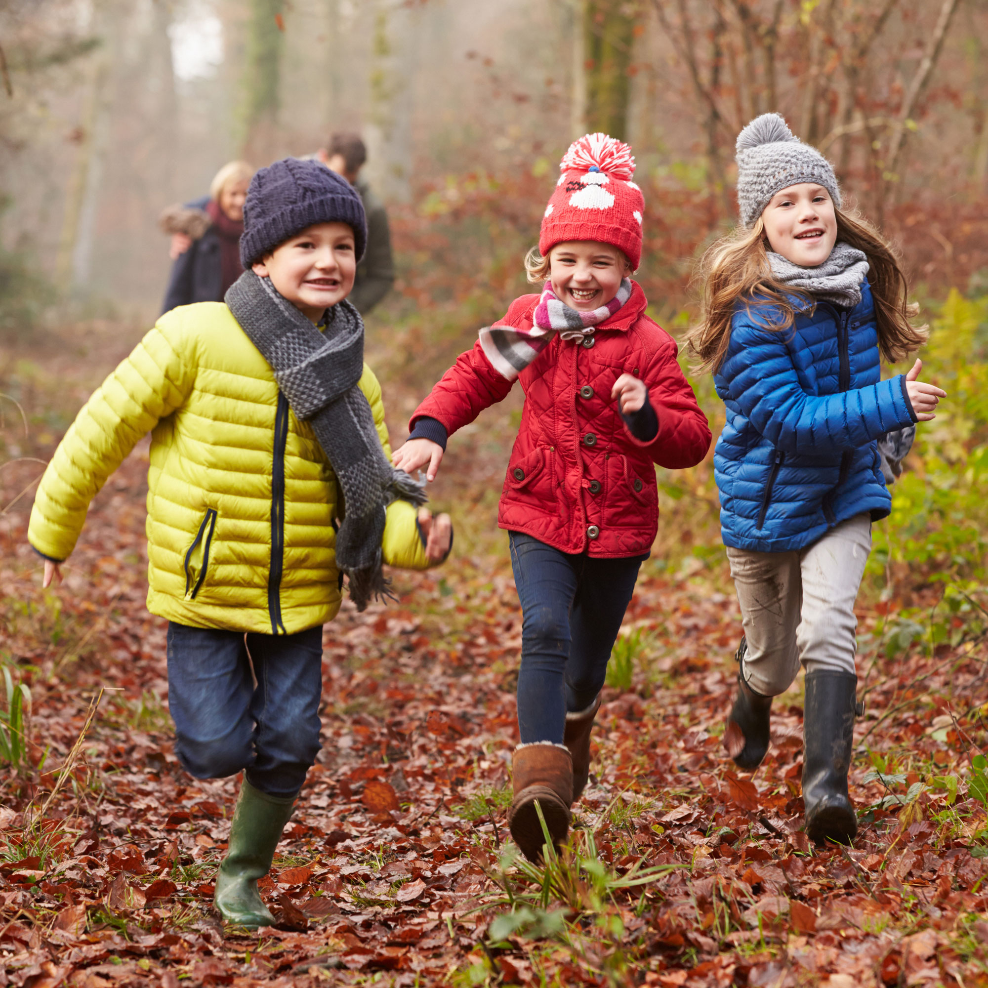 Tre glada barn springer i höstskogen